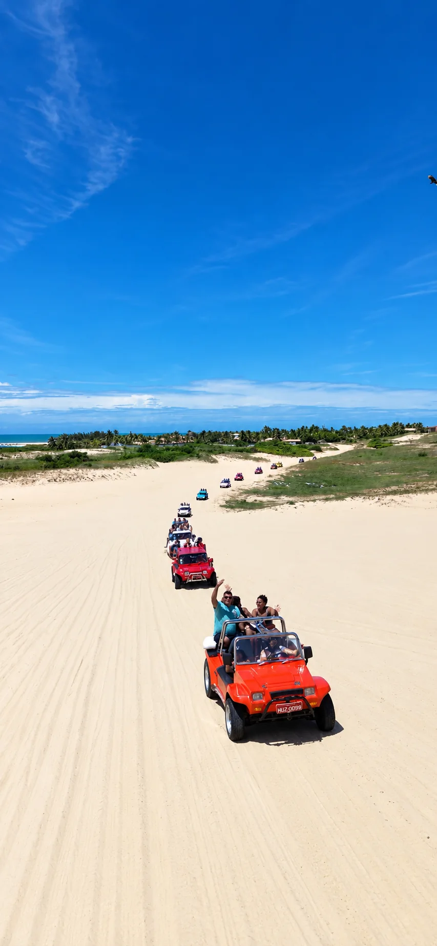 Comboio de buggys atravessando as dunas de Beberibe, com o mar ao fundo